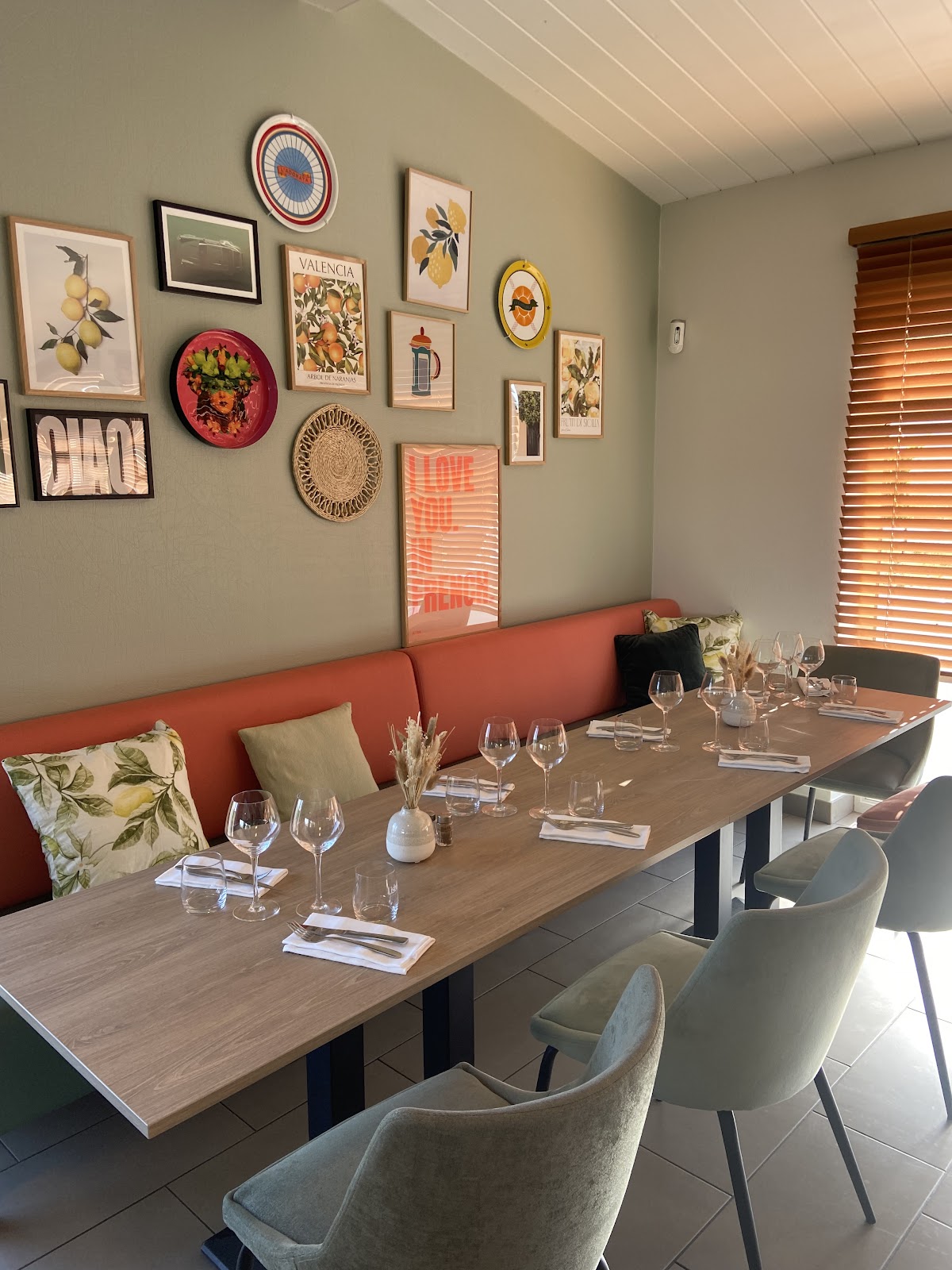 Salle de restaurant avec sofa corail, tables blanches et murs verts