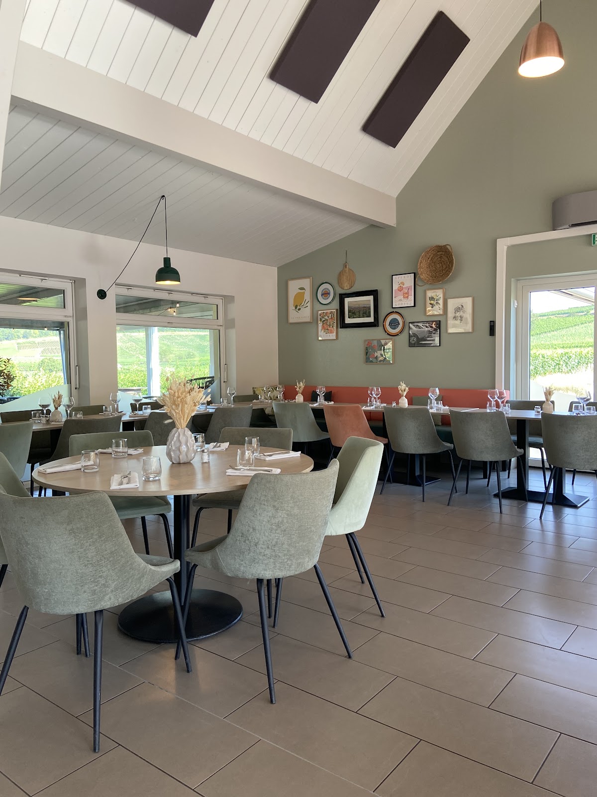 Salle de restaurant avec tables rondes et vue panoramique sur les vignobles